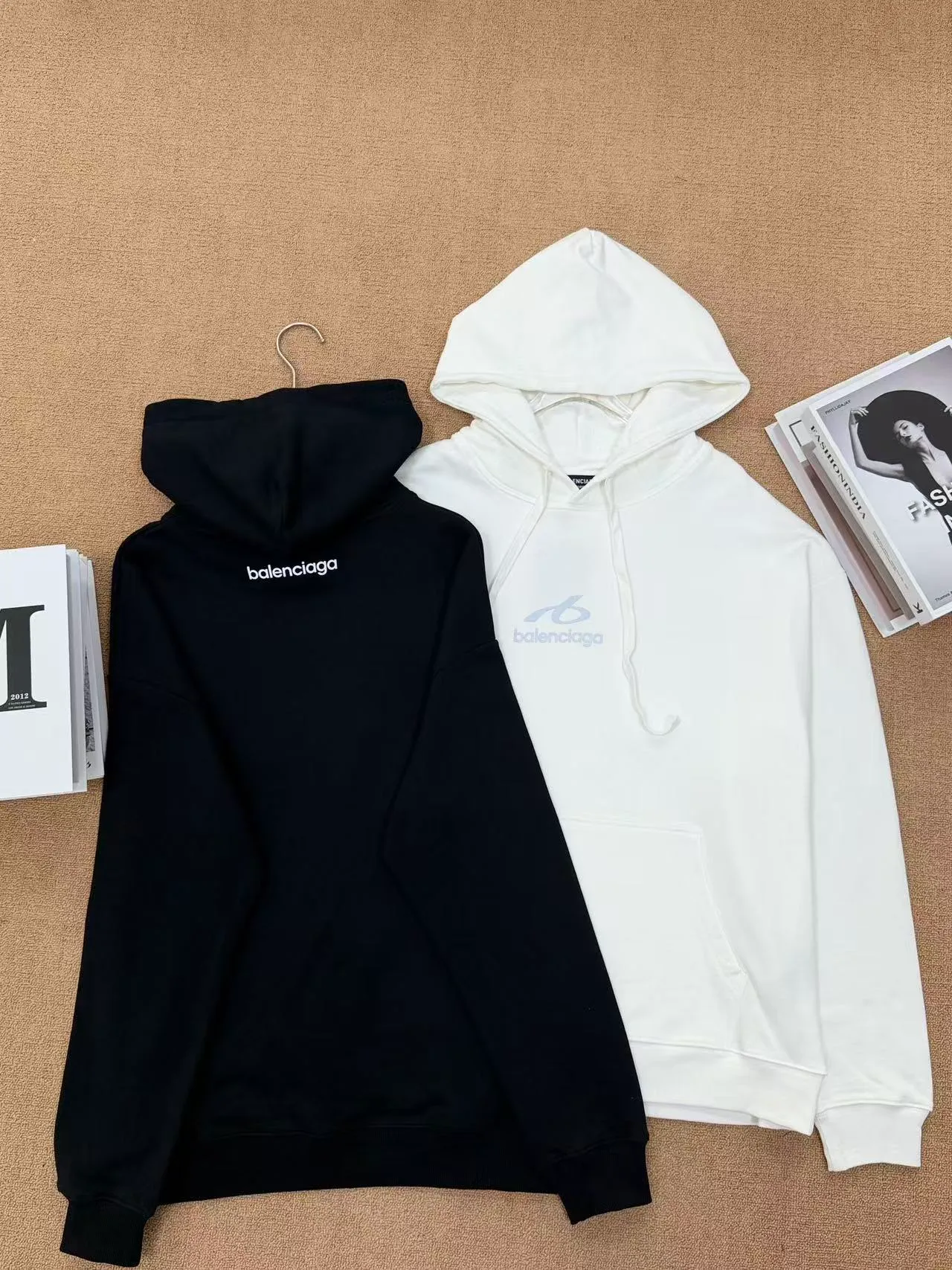 Style No. 2209 Style: Balenciaga small label embroidered hooded sweatshirt Color: Available in Black and Cream White Style: Loose shoulder wide version, same style for men and women, not picky on body shape, with a full, lazy and relaxed feel. Fabric technology: Selected 420g high-weight pure cotton terry fabric, thick and impermeable, soft and delicate to the touch. The logo is simply embroidered on the chest, and the stitching is dense and neat, making it difficult for the thread to come off. The hat has double-layer splicing, a large kangaroo pocket, the drawstring details are in place, and the cuffs and hem are tightly threaded to prevent them from loosening and deforming after long-term wear. Design highlights: Minimalist chest reflective design, no complicated printing, low-key and high-end. Basic black and white Classic color matching, Versatile is eye-catching and not easy to clash with in daily life. The loose cut makes the upper body look slimmer and is very tolerant to all body shapes. Wearing scenarios: Suitable for daily commuting, shopping, and traveling. The bottoms can be paired with jeans, sports pants, or skirts. They can be worn alone. They also look great when paired with a jacket in autumn and winter. A pair for couples will create a great atmosphere.